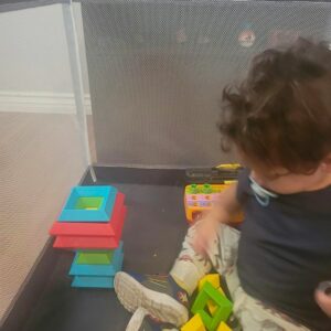 a young child playing with the pyramid stack building blocks