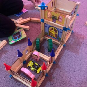 a grandson playing with the wooden building blocks castle