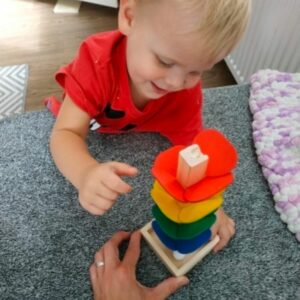 a young boy playing with the wooden tree marble rack