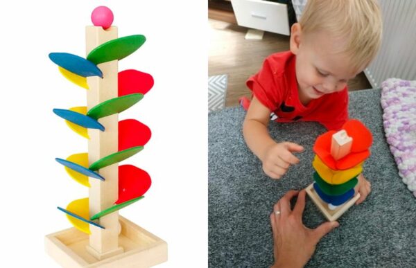 a young boy playing with the wooden tree marble run track